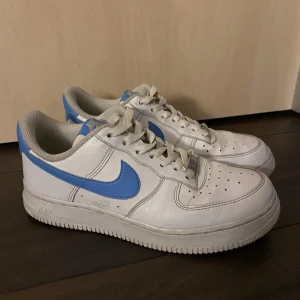 Nike air force 1 sneakers i fint skick! - Vita Nike air force 1 sneakers med blå detaljer. Storlek 38 (24 cm) (Pris kan diskuteras vid snabb affär:)  Använda men i fint skick, inga hål eller tydliga slitningar- se bilder för egen referens