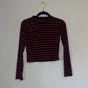 Randig tröja i svart och rött - Tröjan är inte använd och är i bra skick. Väldigt mysigt material som är stretchig, däremot inget märke på plagget.