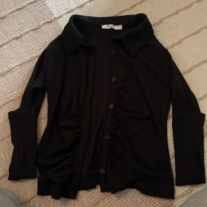 Svart blus - Långärmad svart blus från NA-KD Använd fåtal gånger Säljer på grund av liten i storleken Mycket fint skick Knäppning framtill Säljer för 120kr
