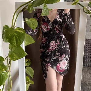 Blommig långärmad midi-klänning  - Blommig overlap-klänning med justerbar snörning i midjan. Använd fåtal gånger. Mjukt skönt material som är väldigt stretchigt 💖