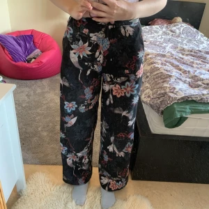 Högmidjade svarta blom mönstriga byxor  - Ganska tunna byxor med blommmönster köpa secundhand, men original från H&M. Inte så varma vilket är toppen nu till sommaren. Lite noppiga, se bild 3. Tryck gärna på köp nu knappen!