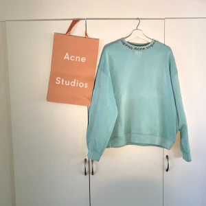 Acne Studios Neck Logo Sweater  - Hej, säljer en väldigt snygg turkos Sweater från Acne Studios. Den är i bra skick. Påse medkommer. Storlek Medium, passar även L. Priset är inte hugget i sten. Hör av dig vid frågor.