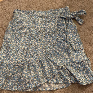 Volangkjol - Ljusblå med vita blommor med lite mörkblå detaljer köpt föra året och använd fåtal gånger nyskick.