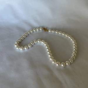 Pärlhalsband av Majorica-pärlor med detaljer i guldpläterat silver och trätt på silkestråd. Halsbandet är 40cm och pärlorna är ca7mm stora. 