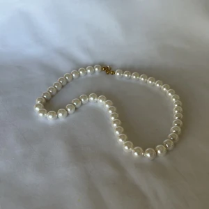 Pärlhalsband - Pärlhalsband av Majorica-pärlor med detaljer i guldpläterat silver och trätt på silkestråd. Halsbandet är 40cm och pärlorna är ca7mm stora. 