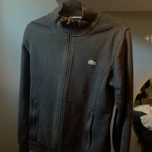Lacoste zip  - Lite solblekt och det finns ett litet hål i ryggen därför billigt pris 