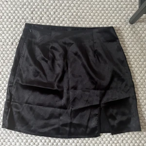 Satinkjol - Svart satinkjol med en liten slits i sidan i strl s/36 