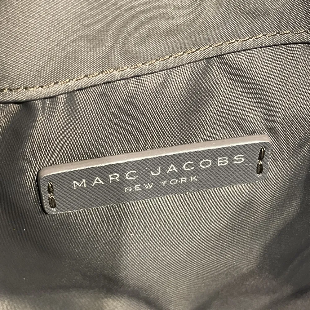 Marc Jacobs handväska köpt i New York. Modell: Nylon sling bag. Färg: Mörkgrå med silver detaljer. Justerbar axelrem, magnet knäppe på locket, ett fack på insidan. Endast använd ca 2 gånger.  Nypris ca 2000kr.. Väskor.