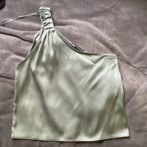 Onesholder linne - Superfint glansigt one-sholder linne i grönfärg. Perfekt till middag eller fest. Använd ca 3 gånger. 
