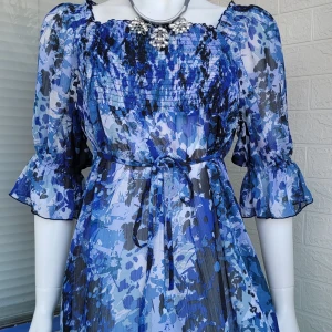 Mönstrad blå tunika i orginalt Ganni stil - Fin, luftig tunika i universell storlek från S-L med elastisk gummi placeras på bröstet i ordningsföljd hudtight look med lösa romantiska ärmar och dekorerad med elegant knytband i mitten av midjan