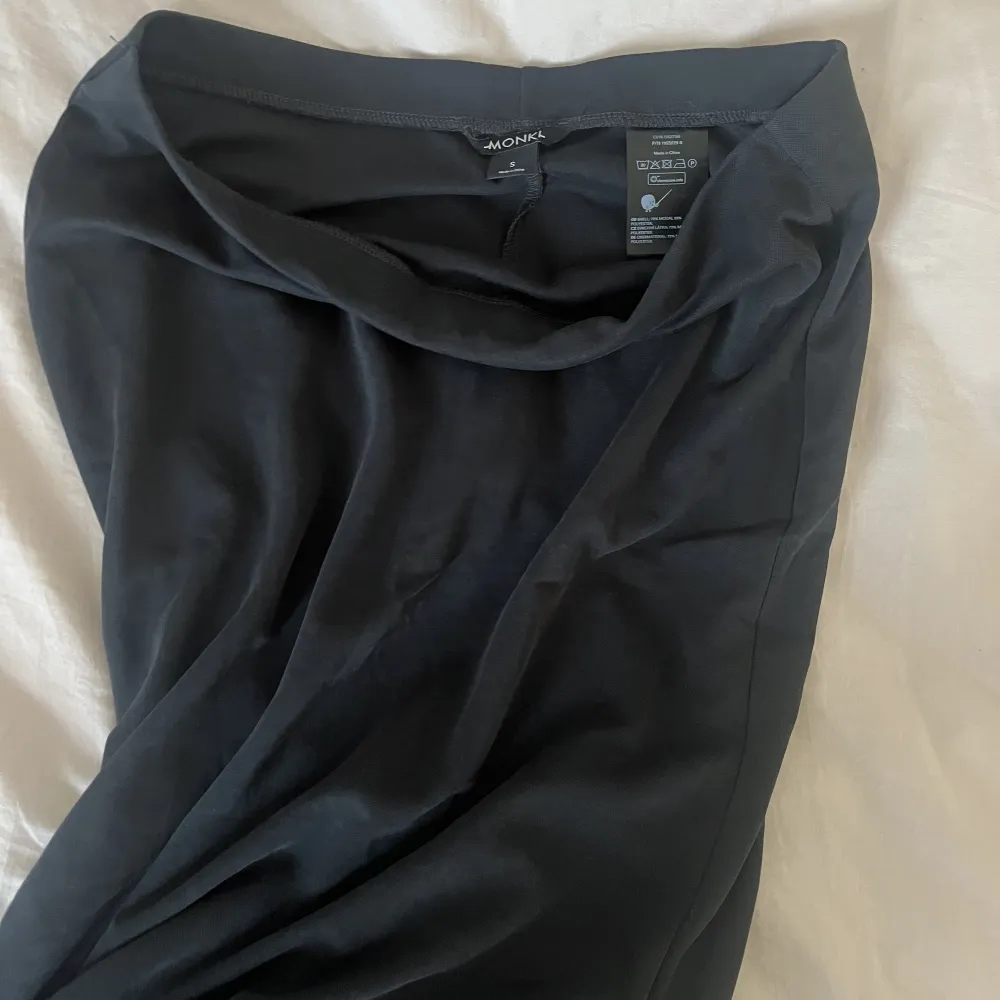 Säljer denna svarta långkjol från Monki då den sitter för löst på mig. Kjolen är använd 2 gånger så skicket är som nytt. Kjolen är inte helt kolsvart som på första bilden utan den är mer grå svart i verkligheten (se bild 2).. Kjolar.