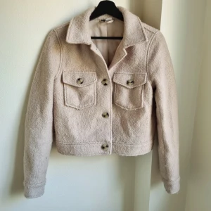 Ull kort jacka - Snygg beige ulljacka från h&m som är använd fåtal gångrr.  Storlek xsmall Ull 43%