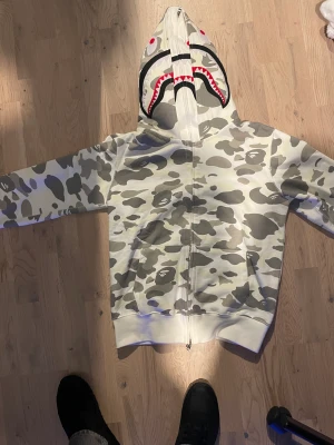 Bape hoodie ÄKTA - Säljer nu min bape hoodie jag köpte på stock X. Den är storlek S och är helt äkta. Kan skicka mer bilder om det behövs. Köpte den för 1 år sen och den är i väldigt bra skick. Dragkedjan funkar perfekt och det är en dubbel hood. Den är glow in the dark.
