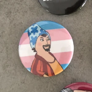 Loranga trans pin - Pin med transflaggan och Loranga från Loranga masarin och Dartanjang. Du kan även byta till en annan flagga/bakgrund 