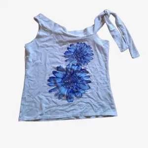 Vit topp/linne med blåa, glittriga blommor & knytning- passar S-L beroende på hur man vill att den sitter