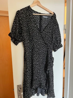 Prickig klänning  - Prickig klänning ifrån missguided med volanger. Storlek 44. Dragkedja i ryggen och knytning framtill. 