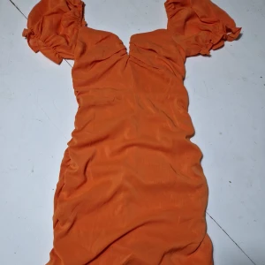 Klänning  - Oanvänd klänning, liten i storleken, rynkad baktill för en smickrande figur.