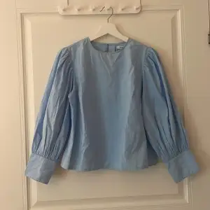 En blus med puffiga ärmar i en fin klar blå färg, nästan aldrig använd 