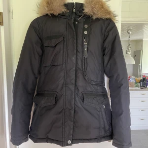 HOLLIES WINTER DAM - Säljer min holliesjacka då den tyvärr inte kommer till användning, endast använd en vinter! Superfint skick, nån fläck som går att tvätta bort. Storlek 36 och sann till storlek. Nypris 5000kr