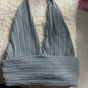 Glittrig topp - NA-KD x Moa Mattson, ljusblå/glittrig topp med halterknytning i nacken. Superfin, oanvänd men lapparna är avtagna.  Biten under brösten är ca 1dm.   Frakt tillkommer eller hämtas i Trollhättan.