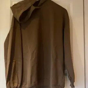 Oversized hoodie med stor luva från GinaTricot i brun. Muddar nedtill samt i ärmslut.