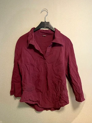 Vinröd blus - Perfekt för kalas. Trekvartsärmar, väldigt skönt tyg, rynkorna i tyget slätas ut ganska mycket bara man tar på den. Engelsk (?) stl 12, passar stl M 38/40. Stretchig. Läs min bio 🤍