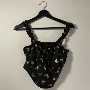 Linne - Oanvänt linne med guldiga fjärilar och knytning längst fram.