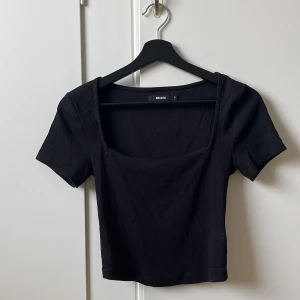 Topp - En kortare t-shirt med urringning. Storlek S, passar även M.