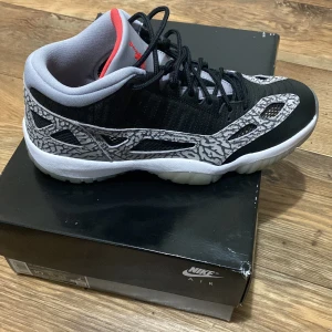 Jordan 11 low IE Black cement - Skick 10/10 endast testade. Köpta från sneakerssuff för 3 år sen. Sitter i lådan utan användning. Kvitto samt original låda finns. De går för minst 180$ för stl 44 på stockx