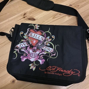 Ed Hardy väska - Datorväska från Ed Hardy med många fack. Väldigt fint skick, inga defekter vad jag kan se. Vid flera intresserade blir det budgivning🖤