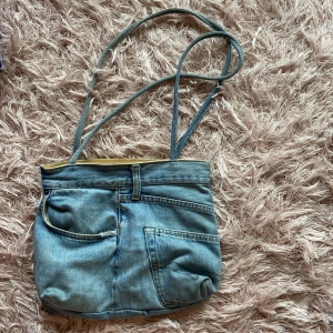 Jeansväska  - Jeansväska med långa axelband och fickor   Mått: 30 cm bred, 25 cm hög