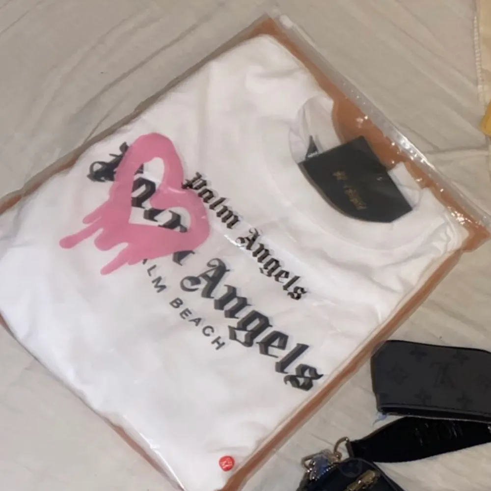 Vit Palm Angels T-shirt med ett rosa hjärta💗Använd 1 gång, Strl M, Nypris 2999. QR-kod finns och den kommer med påsen och alla lappar!. T-shirts.