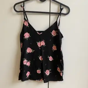 Ett svart linne med rosa blommor som tryck. Använd ett fåtal gånger men är som i nyskick!