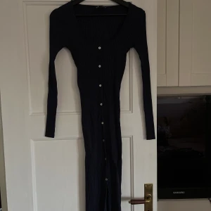 Långklänning - Använd vid ett tillfälle. Långklänning med knappar och slita nertill, framtill på klänningen. Tight passform