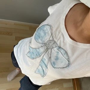 Vit tshirt med rosett - Super fin tshirt med rhinestones detaljer! Har endast använt fåtal gånger, normal i storleken🌸