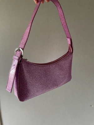 Glitter väska - Lila glitter väska från asos. Tror den inte finns i sortimentet längre. Köpt på Plick för ca 2 år sedan. Kommer inte till användning alls. Men jättefin och bra kvalite, inga defekter 