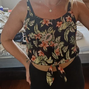 Blommig croptop - Fin croptop från h&m i storlek S. Endast använd fåtal gånger så är i fint skick. Reglerbara axelband och knytband vid midjan.