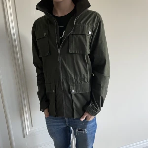 Urberg Fielt Jacket olivgrön. - Säljer denna urberg field jackan som är väldigt bekväm nu under hösten och under vintern. Den säljs inte längre.Kostar 2499 ny pris. Strl M passar för dig som är runt 180. Skick 9,5/10