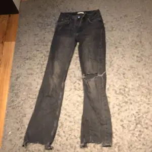 Grå/svarta Mid waist jeans ifrån Ginatricot med ett hål i på ena knäet, i storlek 36 och säljer dom pågrund av att de aldrig kommer till användning längre