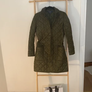 Quiltad grön jacka Ralph Lauren  - Oanvänd grön jacka i quiltat grönt mjukt tyg som är vattenavvisande. Super fin!  Strl 16 år som motsvarar xs.  Köpt på NK i Sthlm förra året. Hämtas på Gärdet eller i stan, eller skickas.  Finns luva till.  //Cecilia 