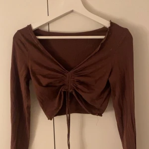 Brun Topp - As fin brun topp, Finns ett litet hål på en av ärmarna men de är inte så synligt. Går att justera längden på toppen me banden.