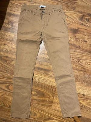 Chinos - Snygga beiga chinos från NNO7. Storlek 30-32. Bra skick och väldigt annvändbara och lämpliga till vardags. Vid intresse av alla tre färger skriv till mig så kan vi lösa en bra deal. 