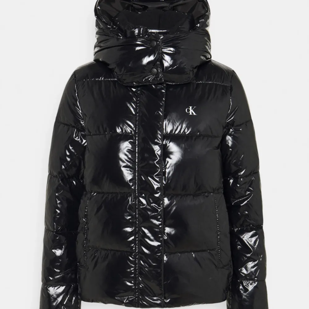 En glansig svart jacka i fint skick från Calvin Klein. Den har även en avtagbar luva. ordinarie pris 2200. Jackor.
