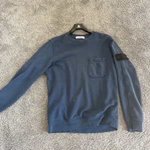 Marinblå Stone Island crewneck - Marinblå Stone Island crewneck med en helsvart patch (ghost patch).  Den är äkta!  Nypris ca 3000kr OBS! GOSTPATCH ÄR EJ KVAR. Har endast en vanlig patch som man kan få om man köper tröjan