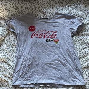 En grå T-shirt med Coca-Cola tryck, storlek s