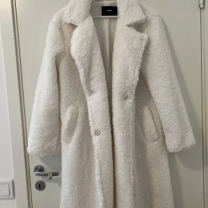 Vit lurvig kappa  - Oanvänd fräsch vit lurv kappa. Den kommer till knäna. Passar bra till vår och höst. Köpt för 900 kr, oanvänd.