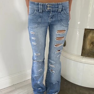 Lågmidjade jeans - Säljer dessa snygga lågmidjade jeansen med hål i. Midjemåttet är 38 och innerbensländen är 82 cm