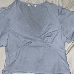 Babyblå blus - Jättesöt v-ringad babyblå blus från nakd med volanger som går att klä både upp och ner