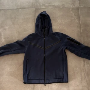 Nike Tech - Säljer nu min blå Nike Tech eftersom att jag inte använder den, har ett litet hål på högersidan av tröjan och därför säljer jag den billigt storlek M