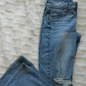 Lågmidjade bootcut jeans med hål  - Ljusblåa jeans, utsvängda ben och hål på ena knäet. Oanvända pga felköp av storlek. Jätte fina nu när det börjar bli varmare ute, väldigt somriga byxor skulle jag säga. Rensar garderoben och vill bli av med allt, därför det billiga priset. Så passa på